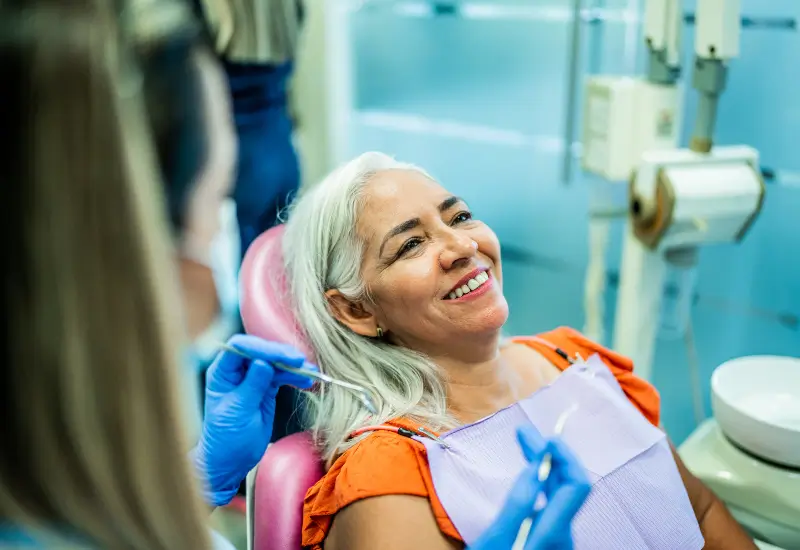 A woman smiles in the chair at her dental office in Parker, CO