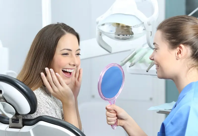 A woman looks in the mirror for the first time after getting her braces removed in Parker, CO.